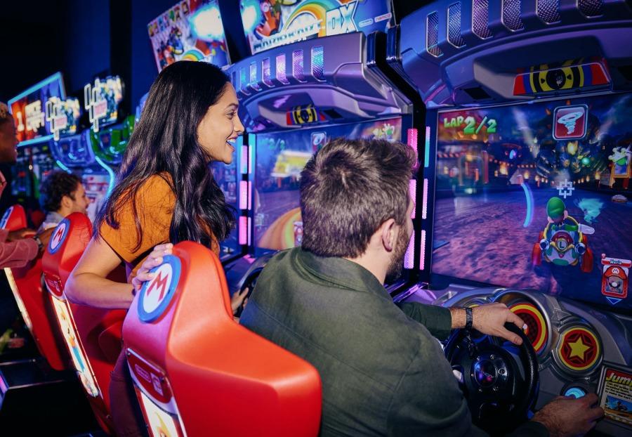 Two friends playing an arcade style driving game.