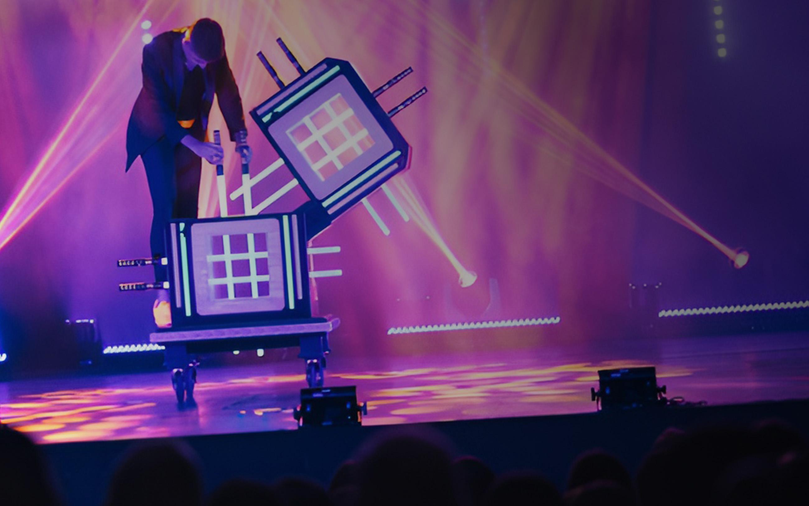 An illusionist performs on stage under spotlights. 