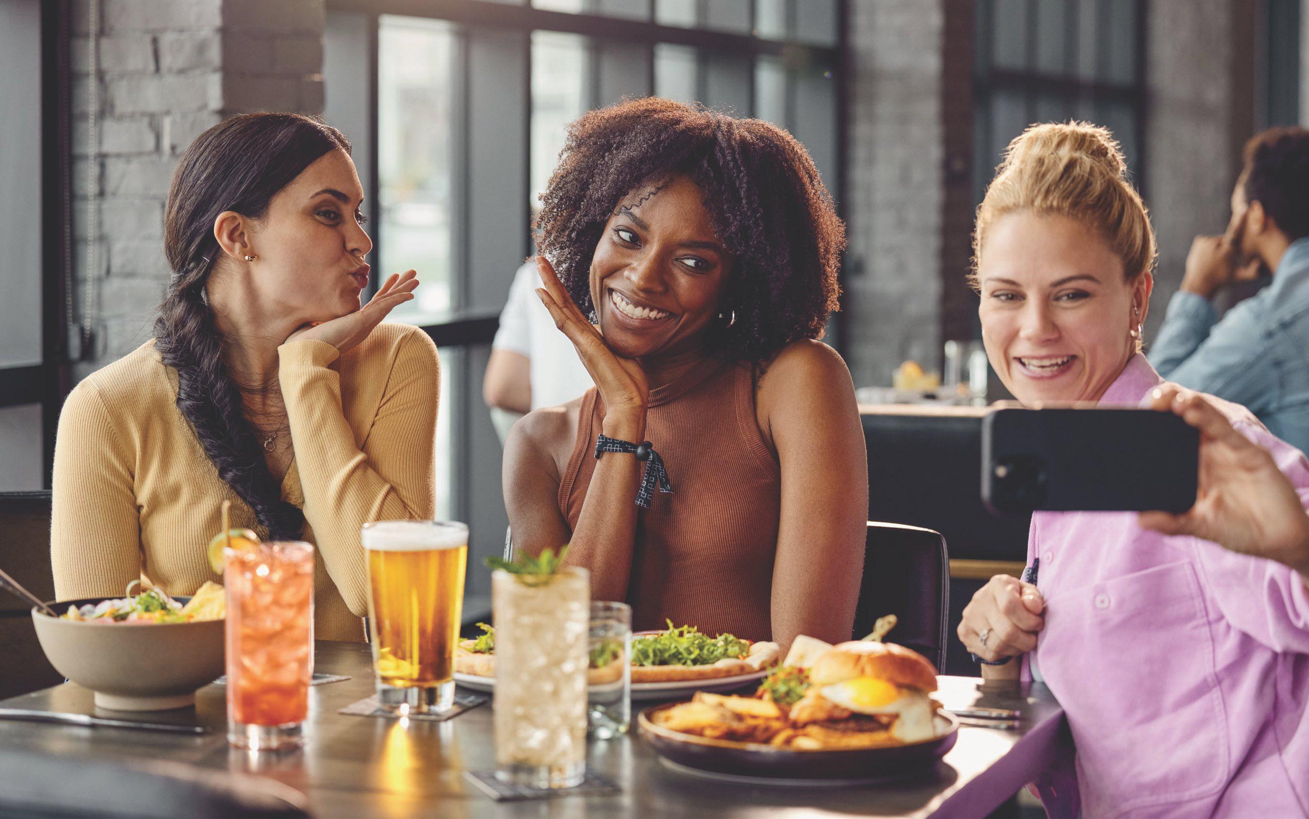 Three women take a selfie in a restaurant while enjoying brunch 