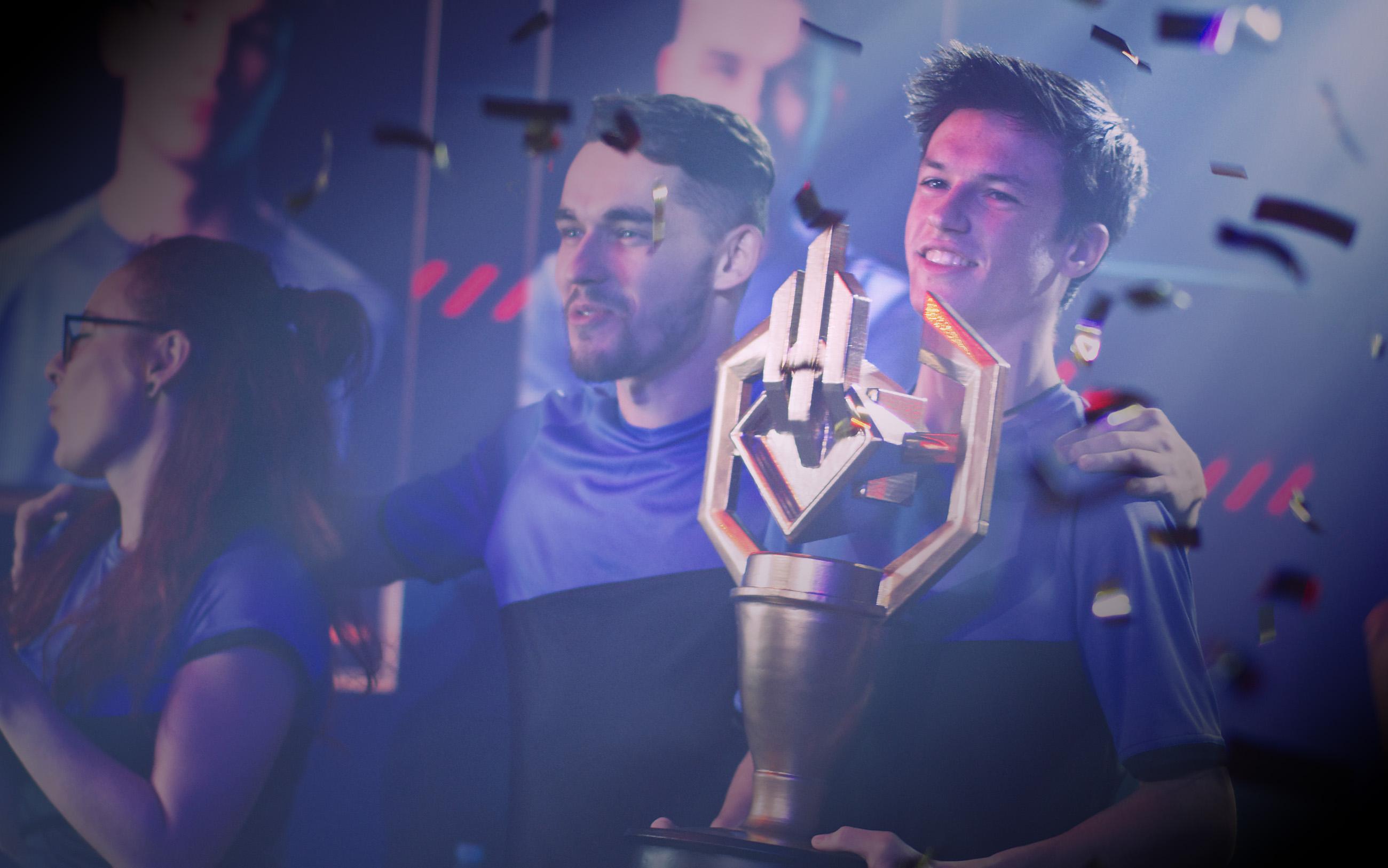 A man celebrates winning an e-sports competition by raising a trophy. 