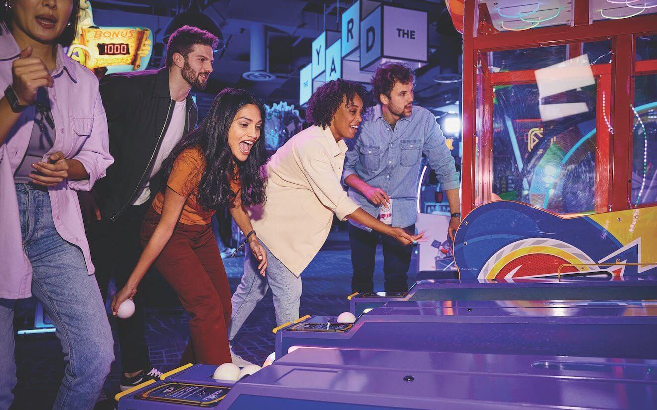 Friends excitedly playing skeeball.